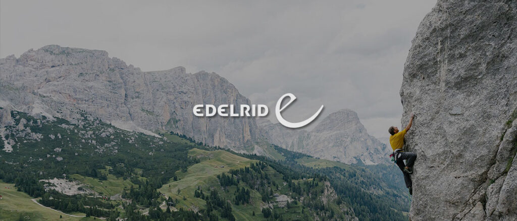 Aussicht auf Berge und einen Sportler der eine Bergwand hochklettert. Das Logo von Edelrid befindet sich in der Mitte des Bildes.