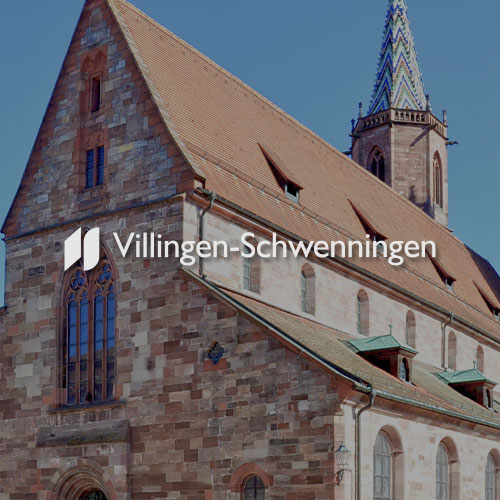 Nahaufnahme einer Kirche in Villingen Schwenningen. Mittig im Bild wird das Villingen Schwenningen Logo dargestellt.