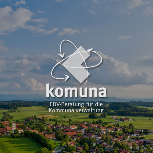 Landschaft mit einem Dorf und Wäldern. Mittig im Bild wird das Komuna Logo dargestellt.