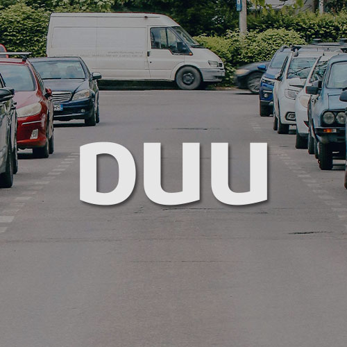 Straße mit Parkpläten. Mittig im Bild wird das DUU Parken Logo dargestellt.