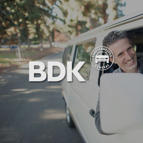 Mann schaut lächelnd aus dem Fenster eines weißen Autos. Mittig im Bild wird das BDK Logo dargestellt.