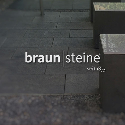 Graue Steinplatten mit grauen Steinhockern. Mittig im Bild wird das Braunsteine Logo dargestellt.