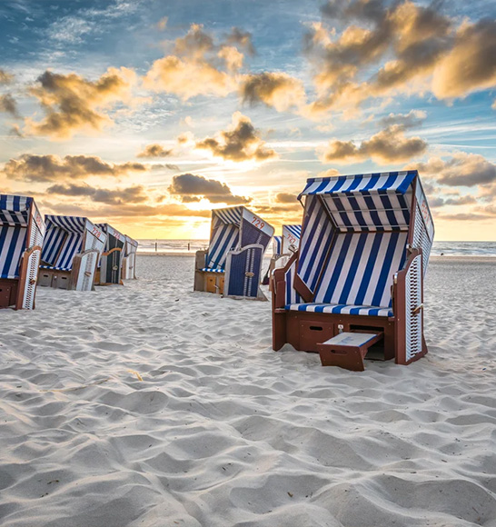 Strandkörbe an einem weißen Strand und im Hintergrund ist das Meer.